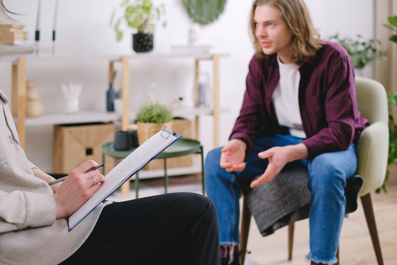 services-03 Professional therapy session with a man discussing with a therapist taking notes indoors.